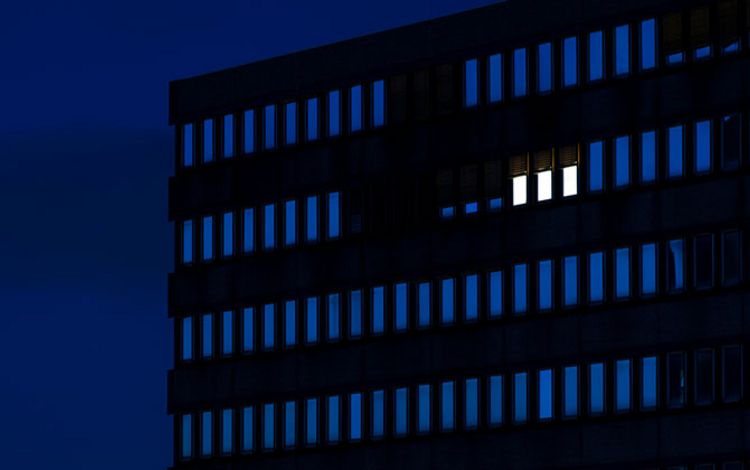 Bürogebäude im Dunkeln mit nur drei erleuchteten Fenster