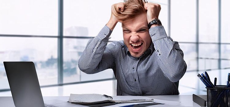 Junger Mann im Büro rauft sich verzweifelt die Haare