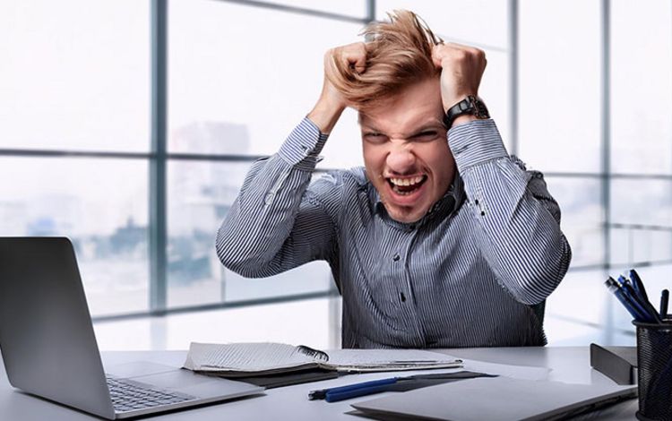 Junger Mann im Büro rauft sich verzweifelt die Haare