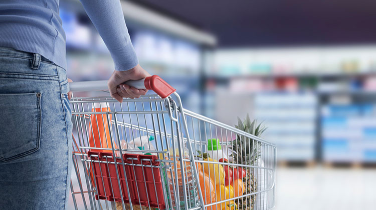 Eine Frau füllt im Supermarkt ihren Einkaufswagen