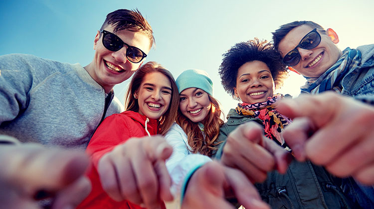 Junge Menschen lachen optimistisch in die Kamera