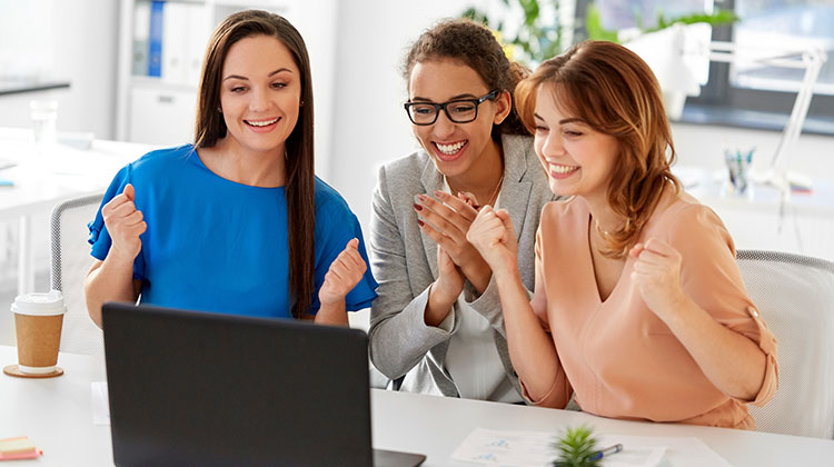 Drei Unternehmerinnen vor dem Laptop, sie freuen sich